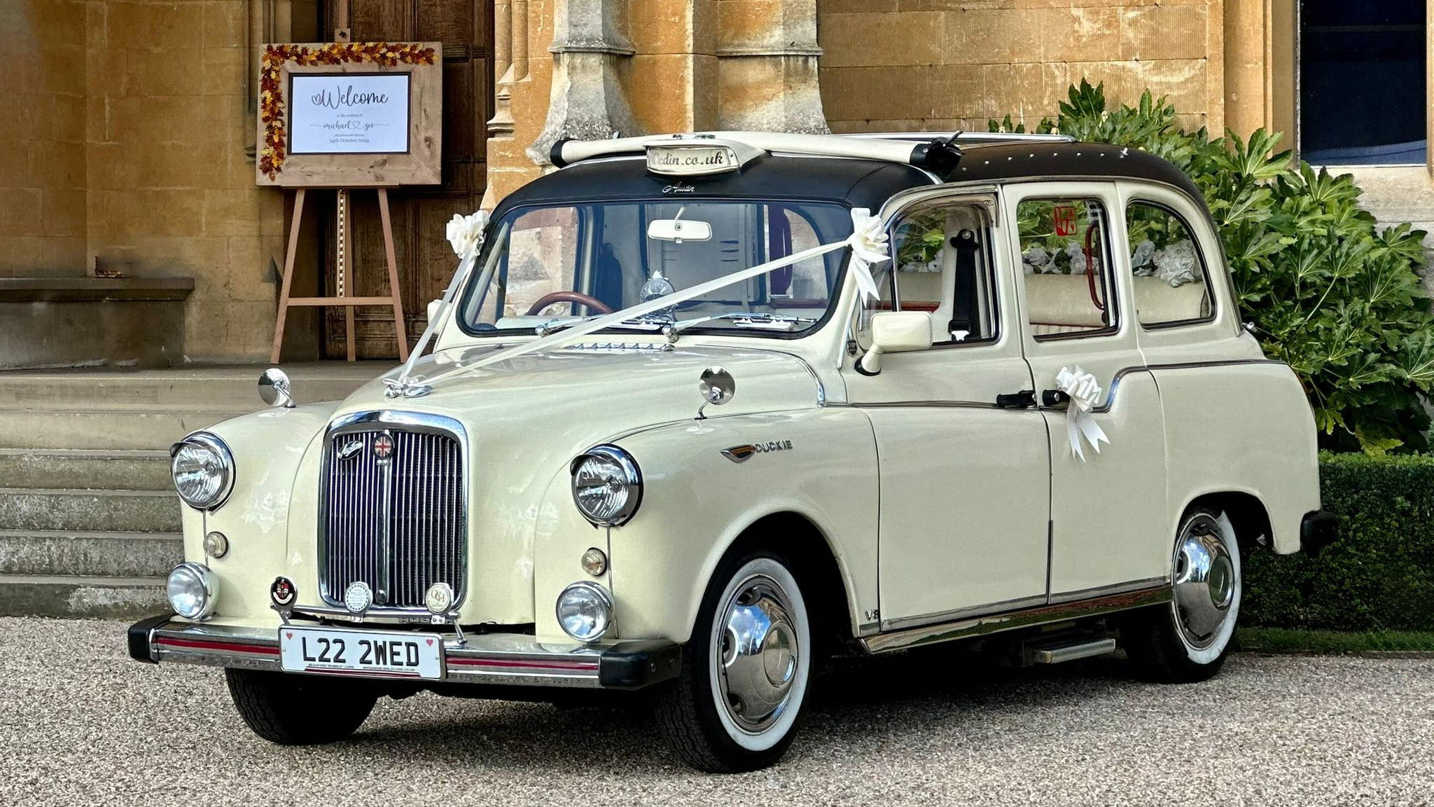 Ivory classic taxi cab for wedding hire with vintage styling, photographed outside a church entrance
