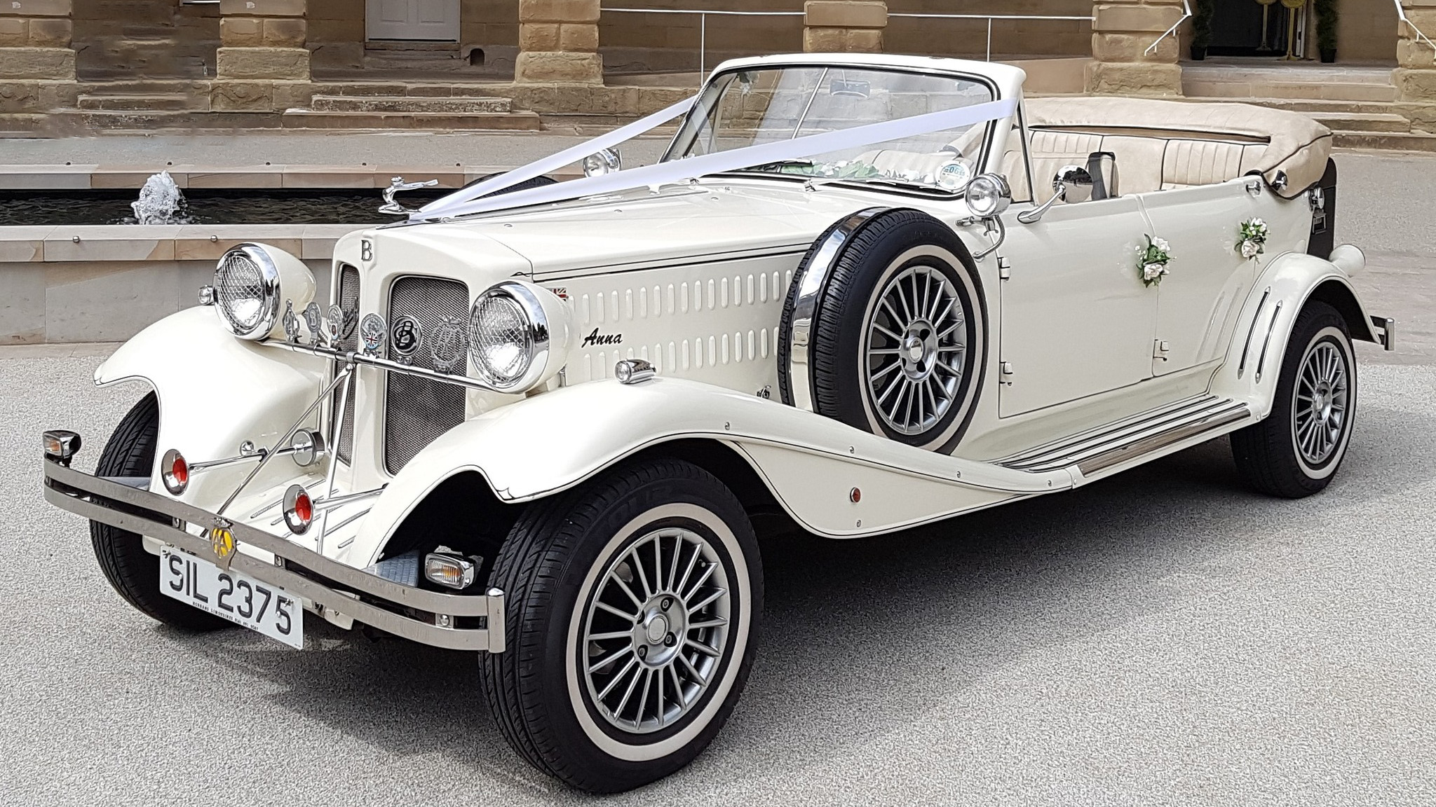 Cream 4 door Beauford convertible wedding car with roof down, parked outside a venue in Warrington.