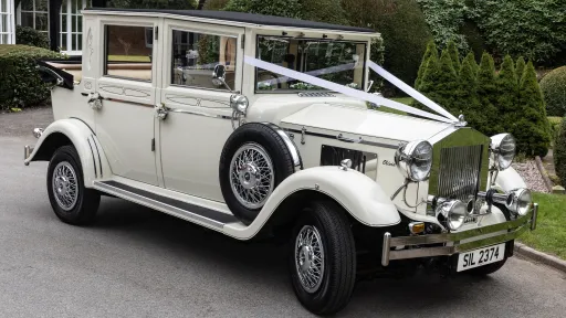 Cream 1930s style Imperial wedding car with chrome headlights and side-mounted spare wheel, parked on a driveway in Cheshire.