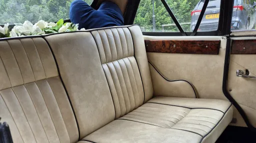 Interior of Beauford wedding car with cream leather seats, door panels and wood trim.