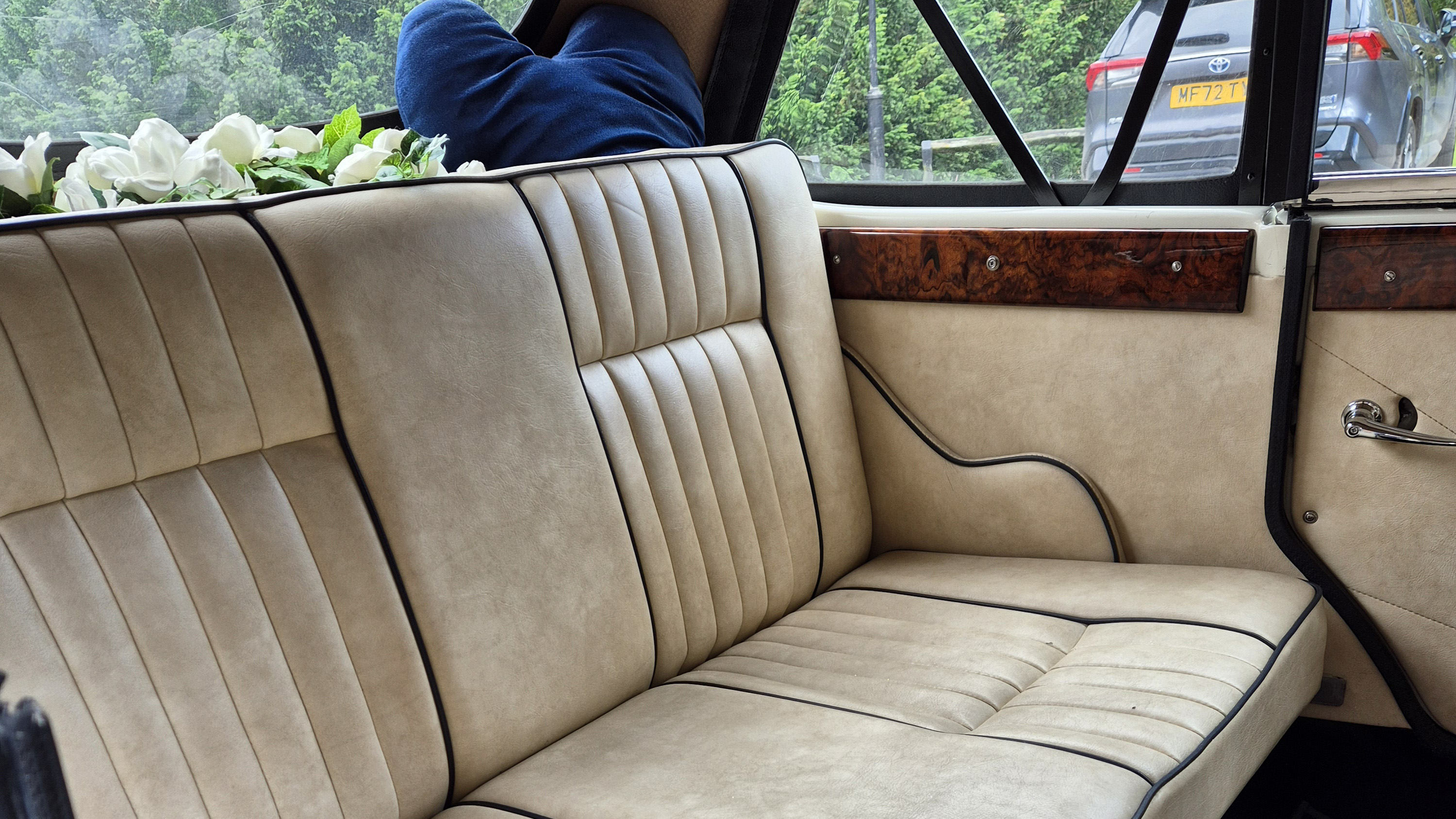 Interior of Beauford wedding car with cream leather seats, door panels and wood trim.