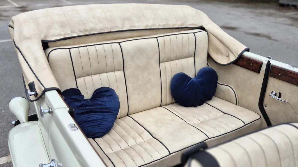 Rear seating area of Beauford convertible with cream leather upholstery and open roof above.