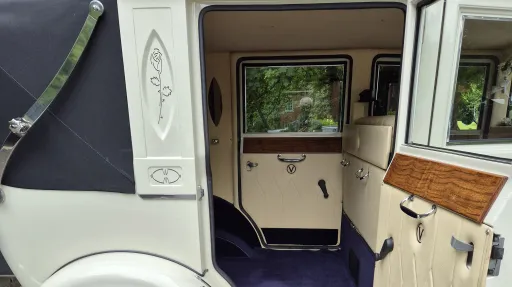 Interior of vintage Imperial car showing cream leather seating, wood trim and spacious rear cabin.