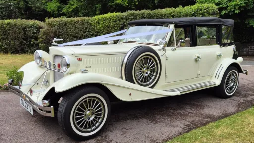 Front left view of cream Beauford convertible with chrome grille, side mounted spare wheel and roof down.
