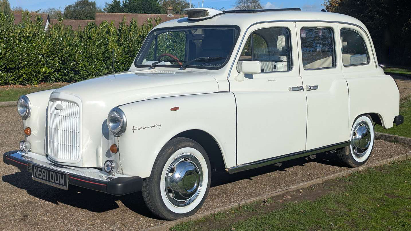 Front left view of classic Fairway taxi cab in Old English White with white wall tyres, parked on a driveway.