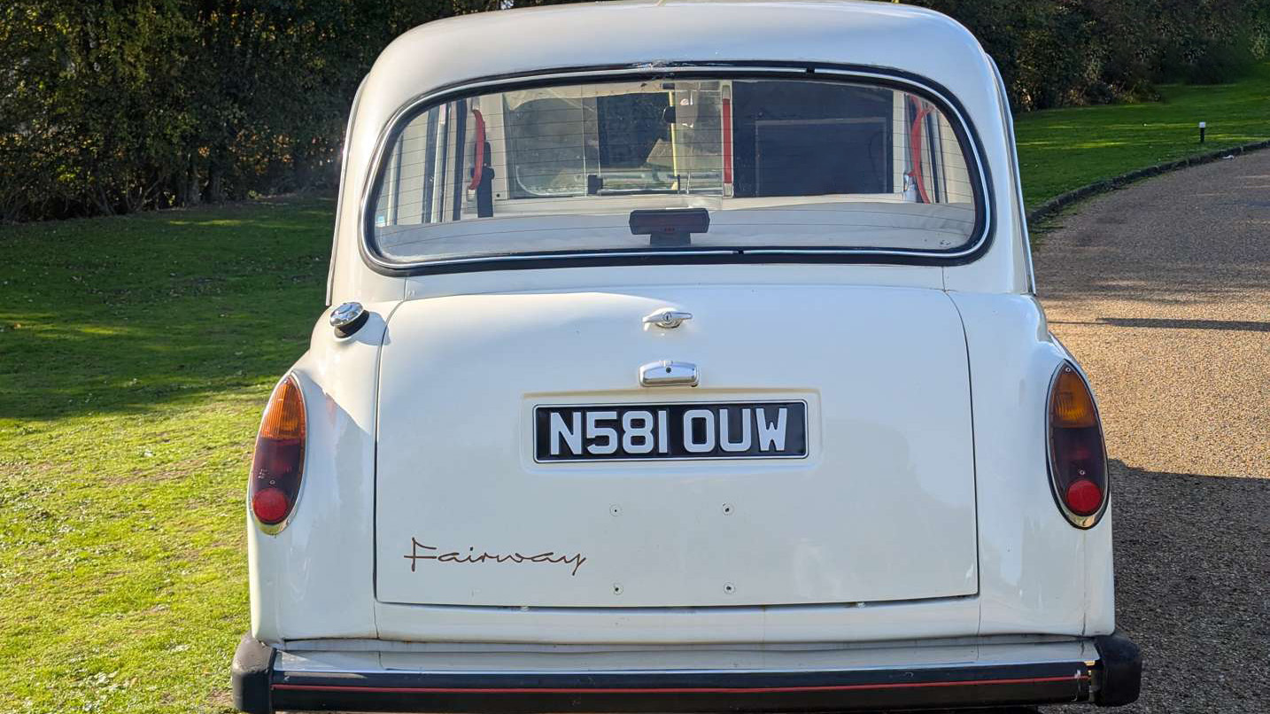 Rear view of classic Fairway taxi cab in Old English White, showing chrome bumper and traditional styling.
