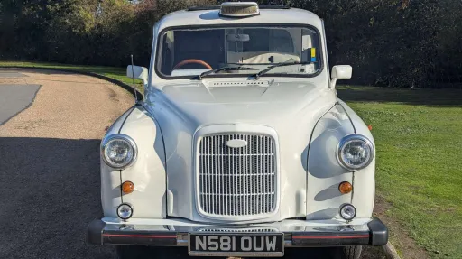 Front view of classic Fairway taxi cab in Old English White with iconic grille and round headlights, ideal for wedding hire.