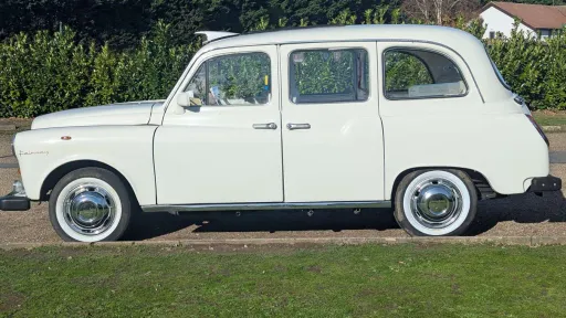 Full side view of white Fairway taxi cab in Old English White with white wall tyres, parked on grass.