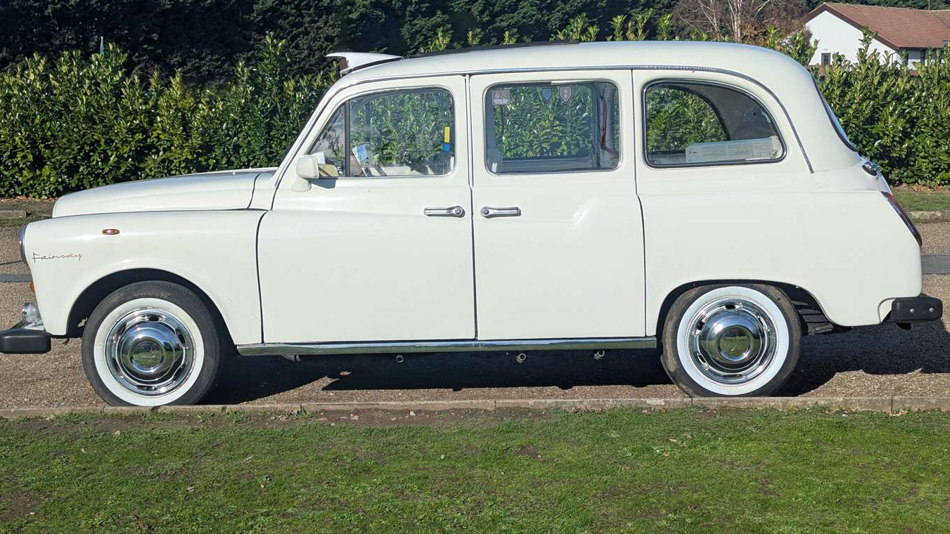 Full side view of white Fairway taxi cab in Old English White with white wall tyres, parked on grass.