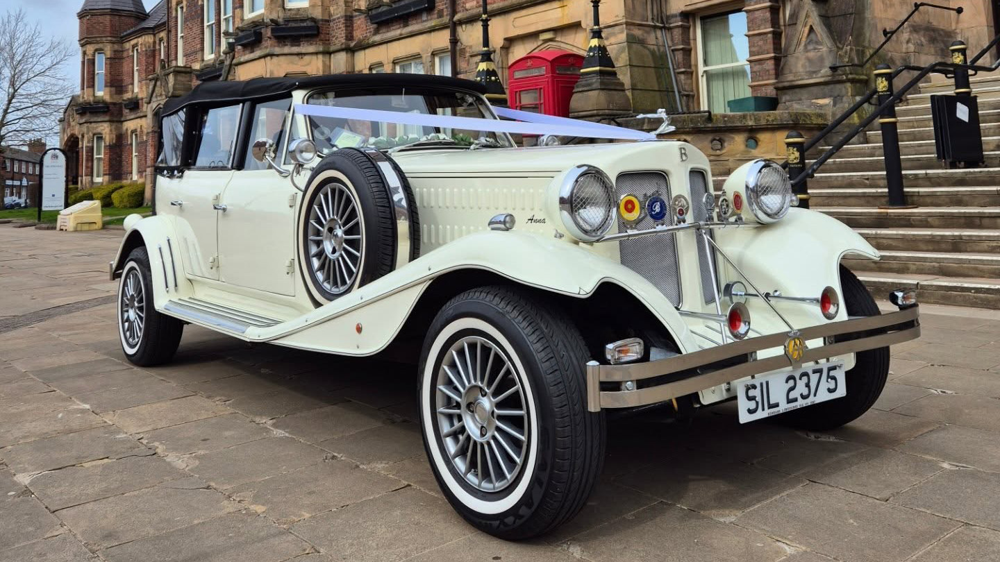Cream Beauford convertible with wedding ribbons, roof folded down and chrome features visible.
