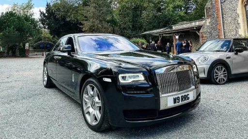 Black Rolls-Royce Ghost parked at a wedding with wedding guests in the background
