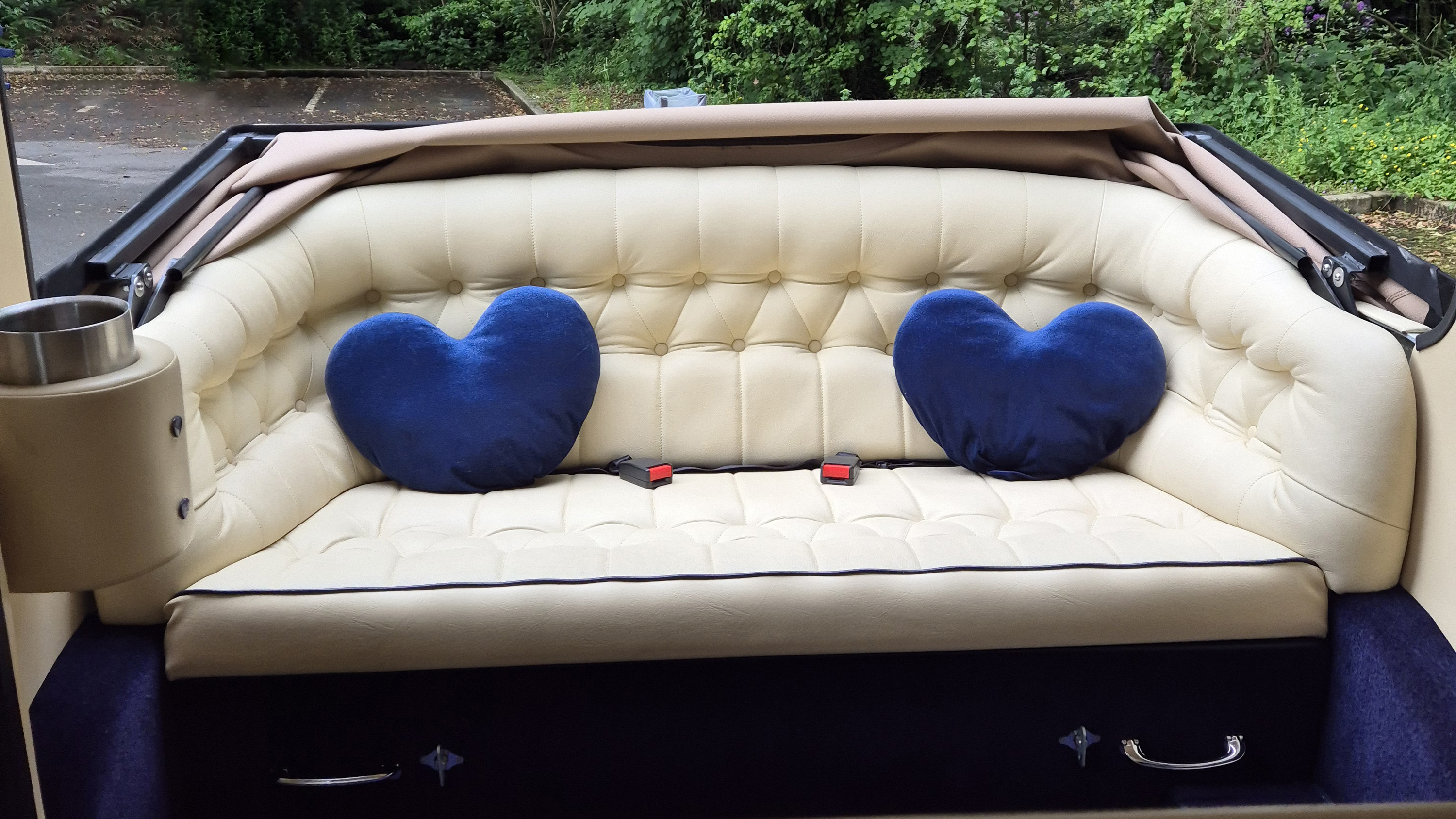 Rear bench seat of Imperial wedding car in cream leather with buttoned upholstery and spacious seating area.