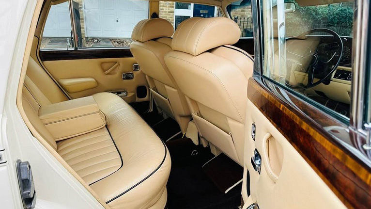 Interior of Rolls-Royce Silver Shadow Mk2 with cream leather seats, wood trim and spacious rear cabin with legroom.