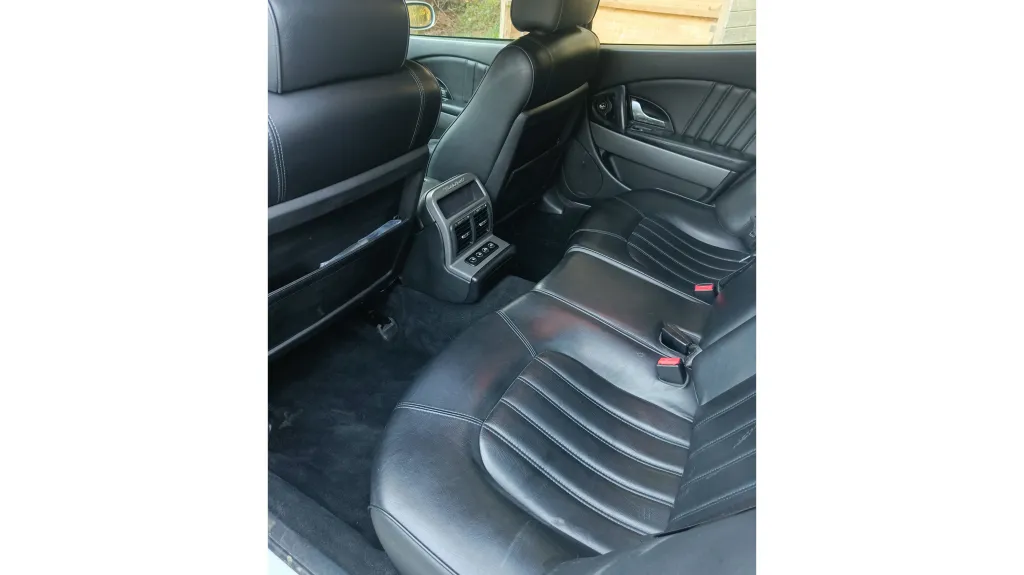 Rear interior of Maserati Quattroporte showing black leather seats, centre console and modern luxury cabin finish.