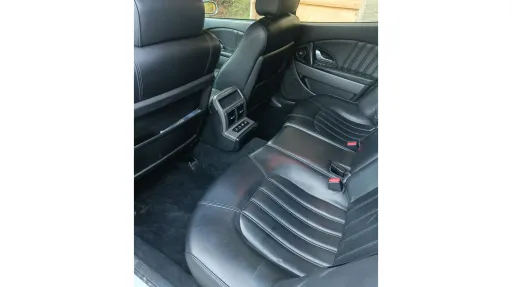 Rear interior of Maserati Quattroporte showing black leather seats, centre console and modern luxury cabin finish.