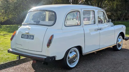 Rear right view of classic Fairway taxi cab in Old English White, based in Devon, parked on a quiet road.