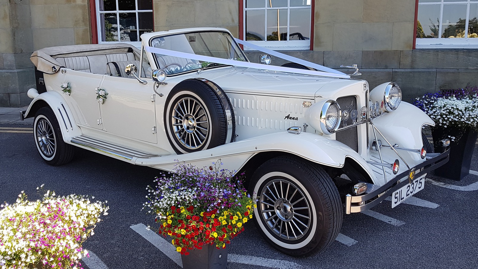 Cream Beauford convertible wedding car parked outside a venue in Cheshire with roof open.