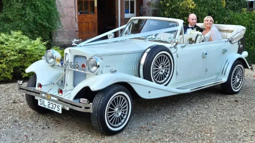 Wedding couple seated inside cream Beauford convertible at a venue in Warrington, roof down.