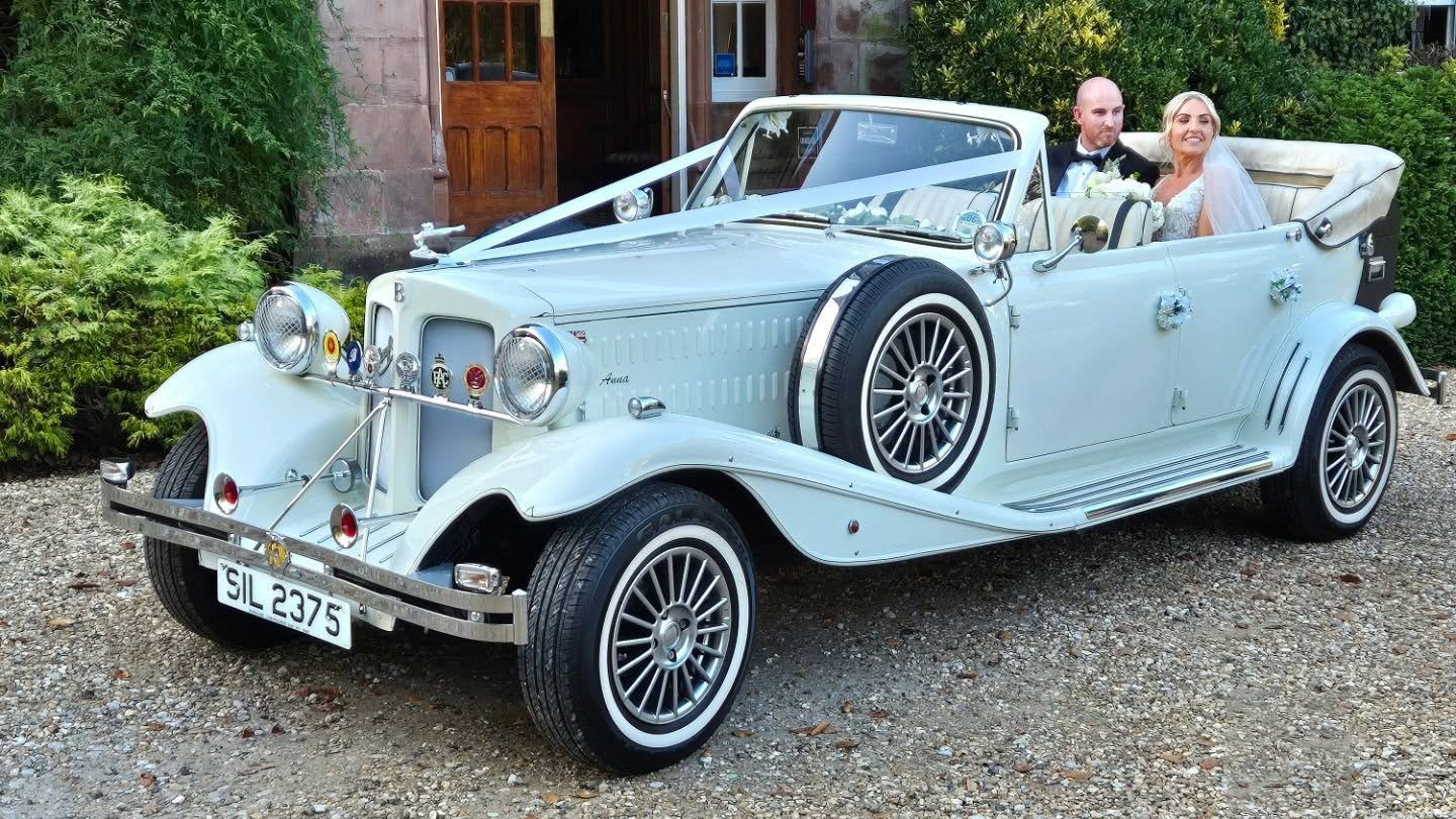 Wedding couple seated inside cream Beauford convertible at a venue in Warrington, roof down.