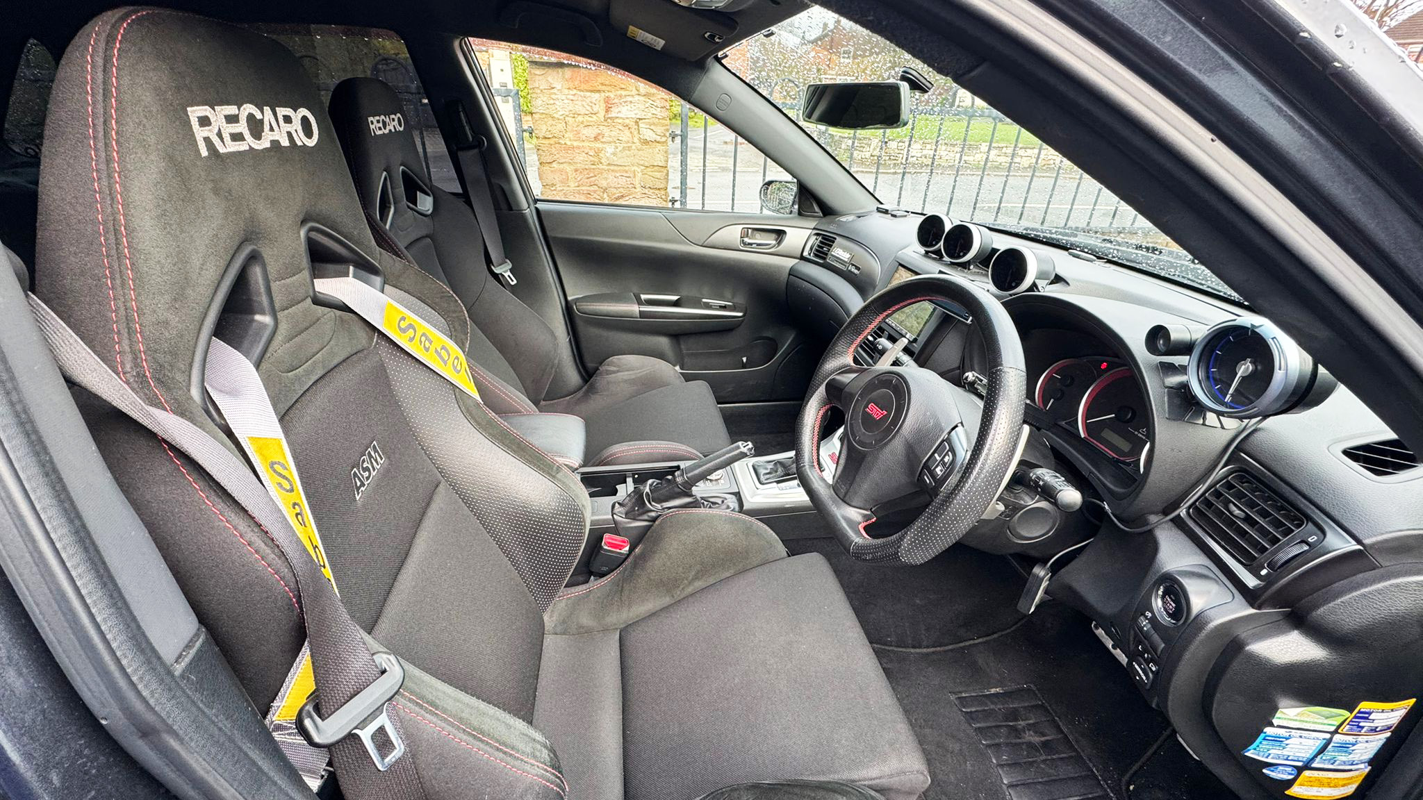 Front interior of Subaru Impreza showing sporty bucket seats, steering wheel and dashboard, dark upholstery with performance styling details.