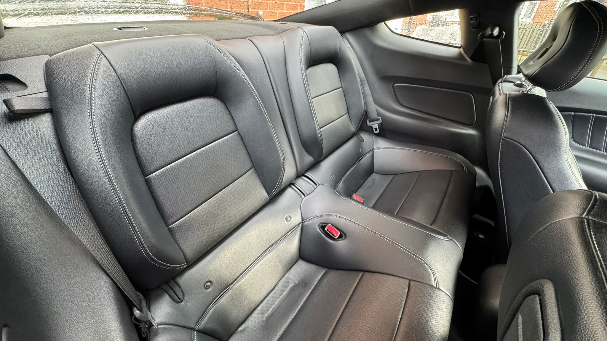 Rear interior of Ford Mustang GT showing two rear seats in black leather, compact cabin space.