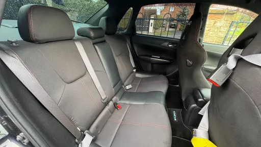 Rear passenger seats inside Subaru Impreza, dark upholstery with seating for three, compact cabin space.