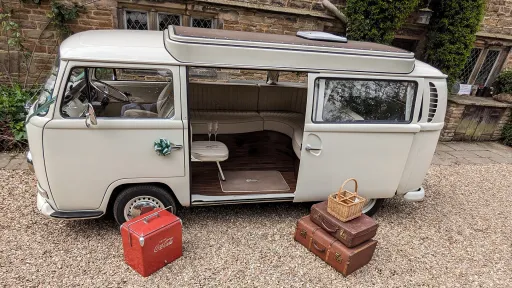 Fill left side view cream Campervan with period suitcse outside rear open door with interior showing cream leather seating