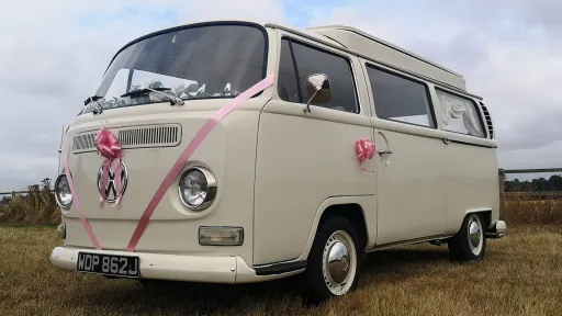Front left angle VW campervan with wedding ribbons and bows, doors closed, countryside wedding setting