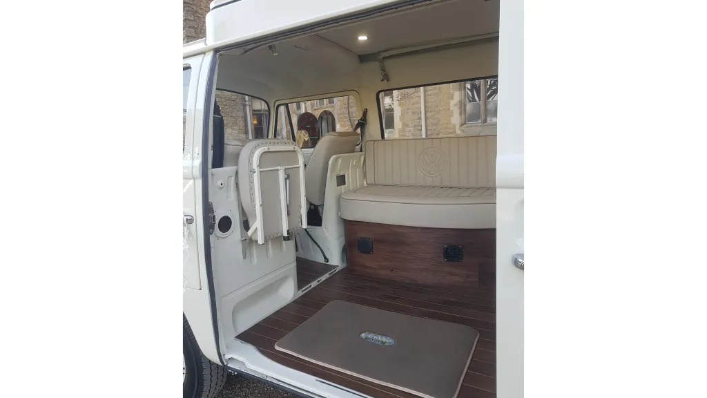 Campervan interior showing seating for up to 7 passengers with cream upholstery, side door open