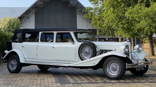 White Beauford Landaulette limousine side view parked on driveway, long body 7 seater with vintage chrome details