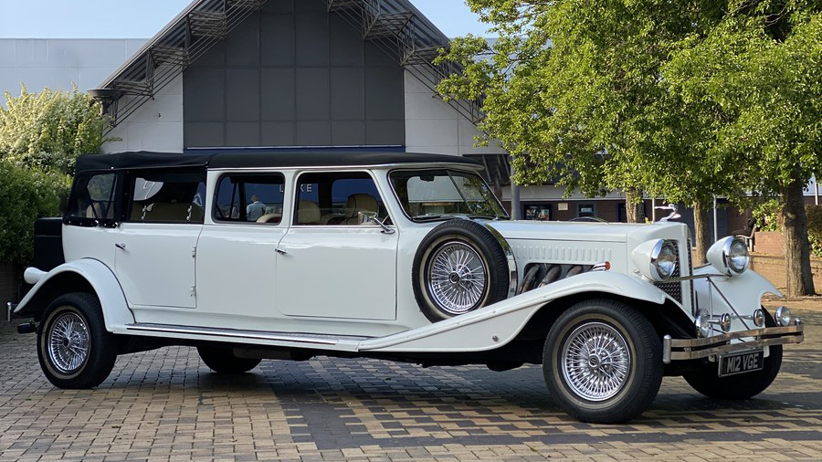 White Beauford Landaulette limousine side view parked on driveway, long body 7 seater with vintage chrome details