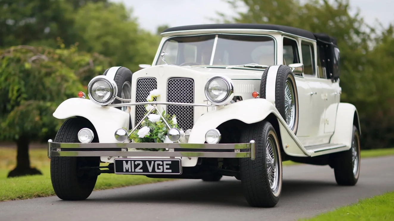 Left front angle of white Beauford Landaulette limousine with chrome grille and long vintage body
