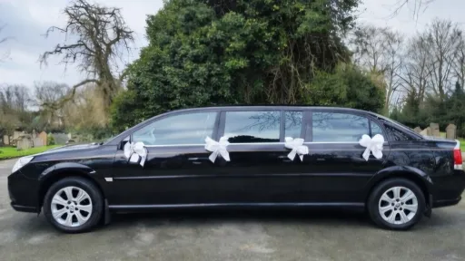 Left side exterior view of black stretched Vauxhall Vectra limousine with white wedding bows on door handles