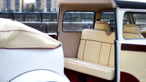 Rear facing cream leather bench seat inside Beauford limousine with classic vintage cabin layout
