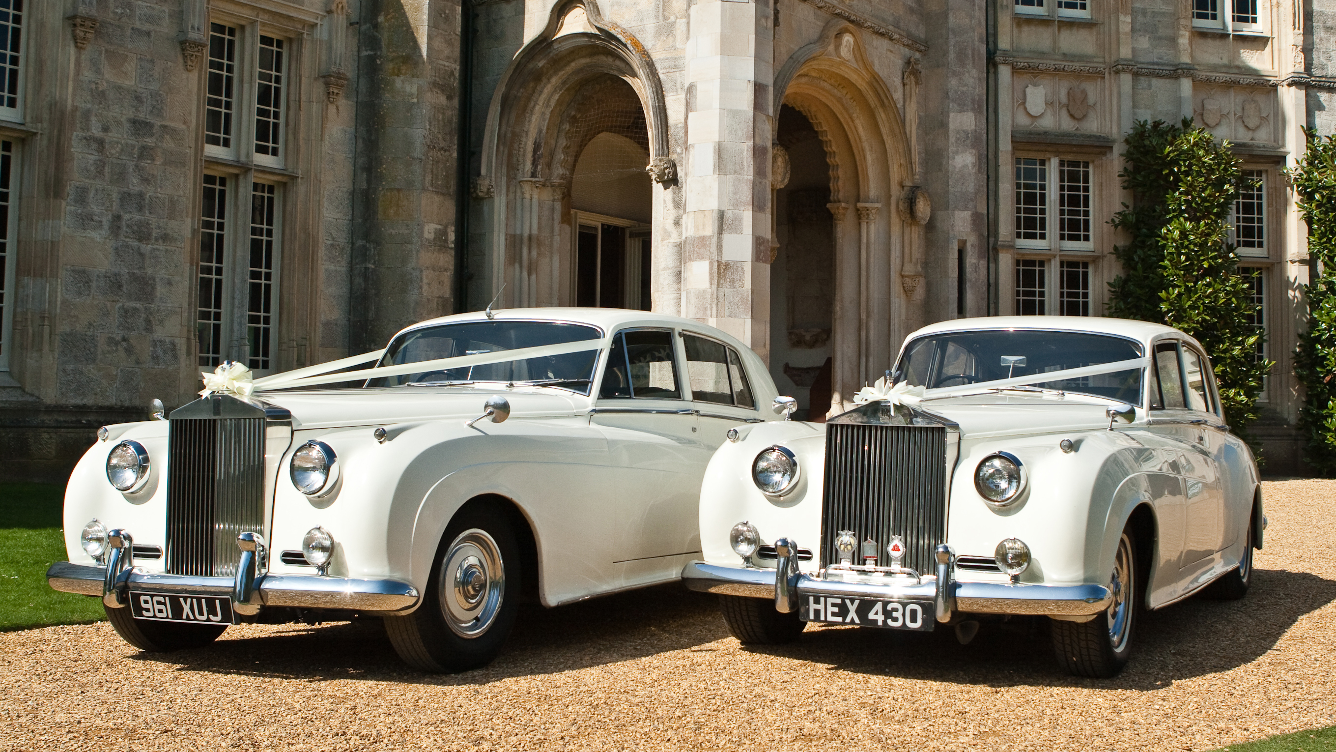 Two classic Rolls-Royce Silver Cloud cars in Old English White parked side by side outside grand building