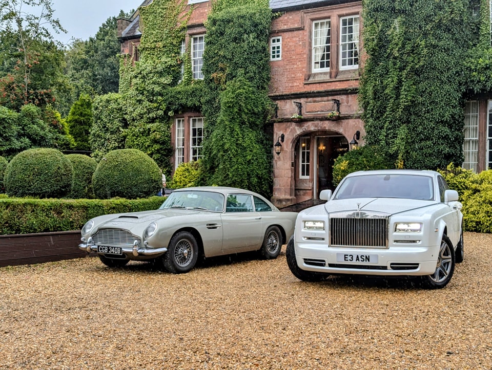 Iconic Astion Martin DB5 parked next to a modern White Rolls-Royce Phantom outside a local wedding venue in East Lothian