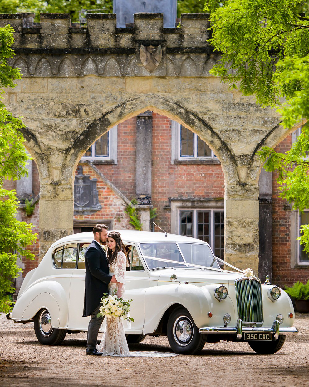 Classic 7-seater Austin Princes Limousine in Ivory with Bride and Groom holding each other’s ion front of the vehicle