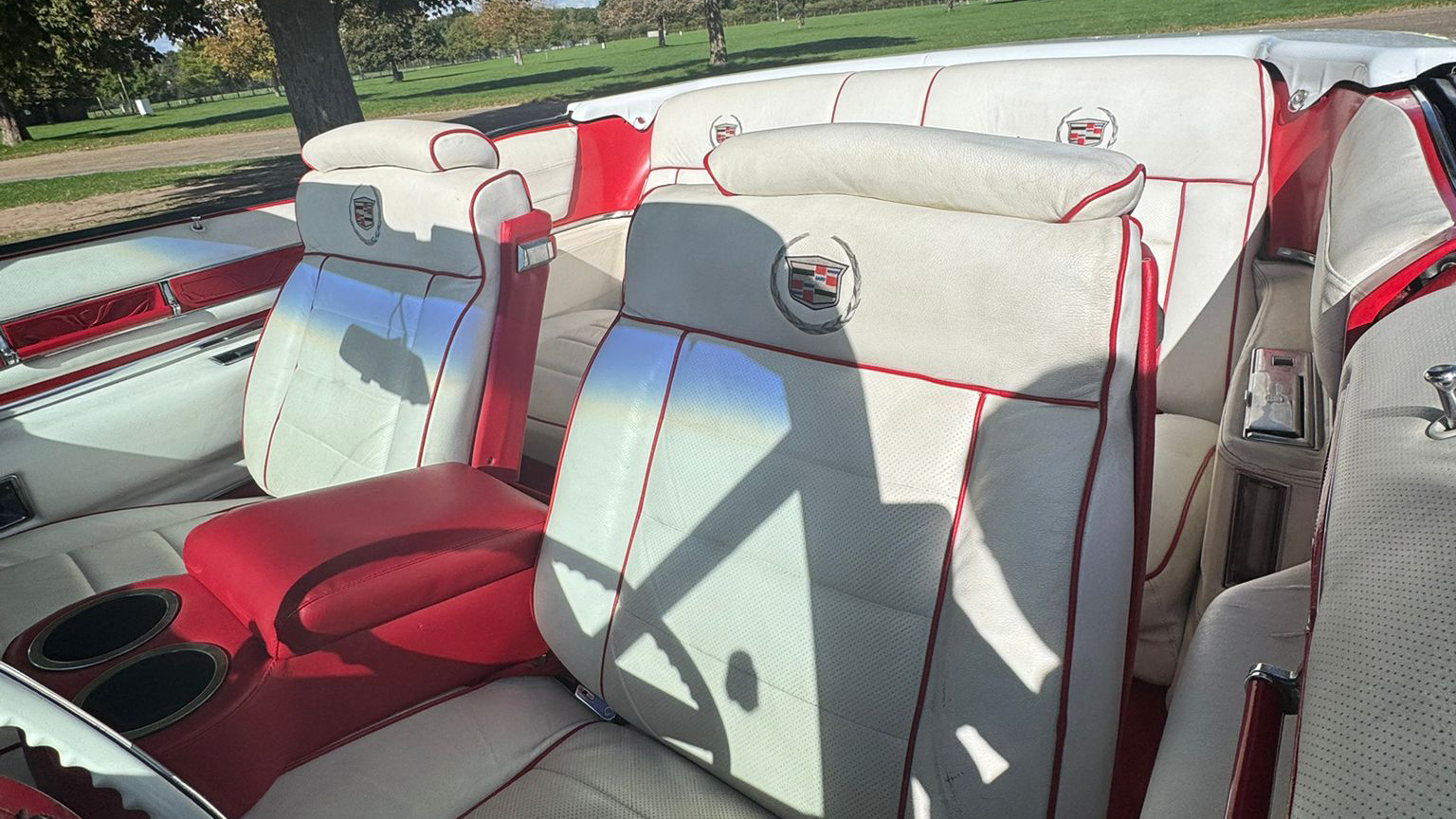 White and burgundy piping interior inside a 1975 Cadillac Eldorado convertible wedding car with luxury bench seating and folded soft top roof in East Anglia