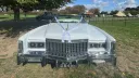 Front view of classic white 1975 Cadillac Eldorado convertible wedding car with wedding ribbons attached to chrome grille and roof folded down