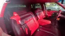 1990 Cadillac Brougham burgundy red leather interior, rear cabin angle, chrome accents, deeply cushioned seating.