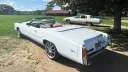 Rear side view of white Cadillac Eldorado convertible wedding car with cream and burgundy seating, folded roof and long classic American body styling in East Anglia