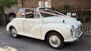 Classic Morris Minor Convertible parked outside a wedding venue in Kent, finished in Old English White with chrome hubcaps and black folding roof.