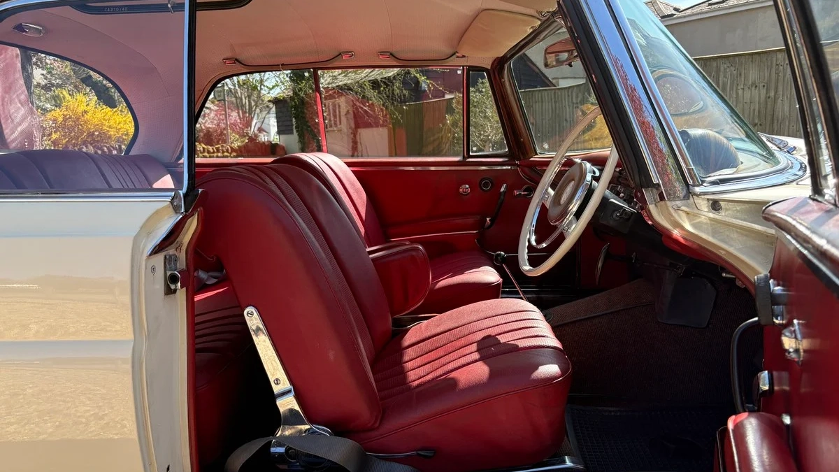 Classic Mercedes 250 SE Coupe interior with rich red leather seats, wood dashboard and vintage steering wheel.