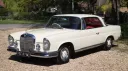 Ivory Mercedes 250 SE Coupe wedding car parked on gravel with chrome trim and red leather interior.