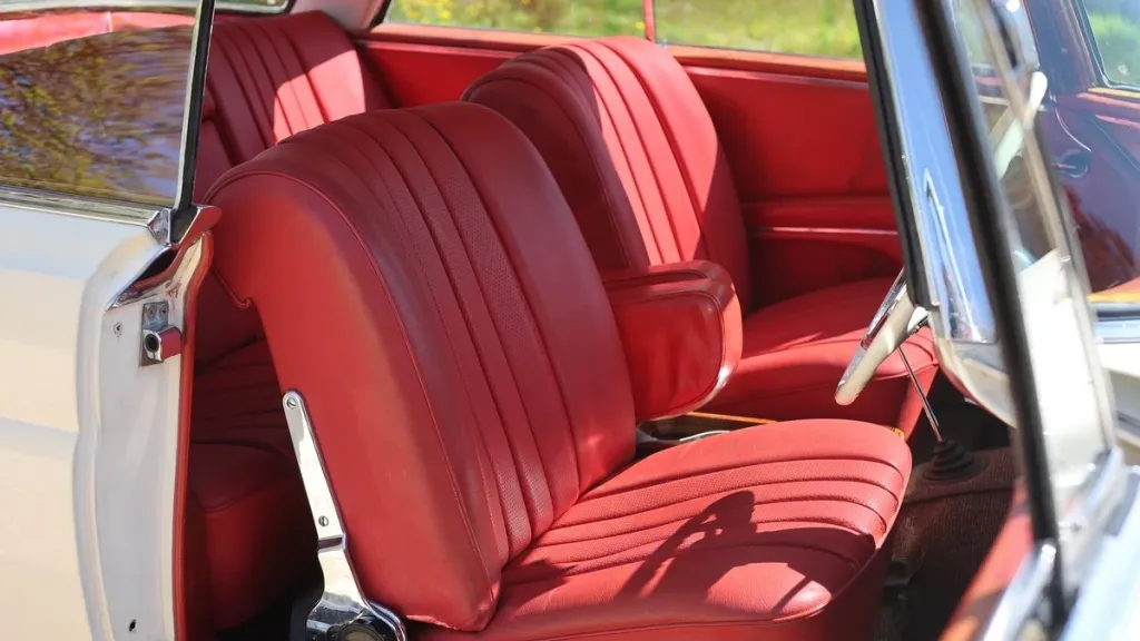 Open-door view of the Mercedes 250 SE Coupe showing burgundy red leather front seats.