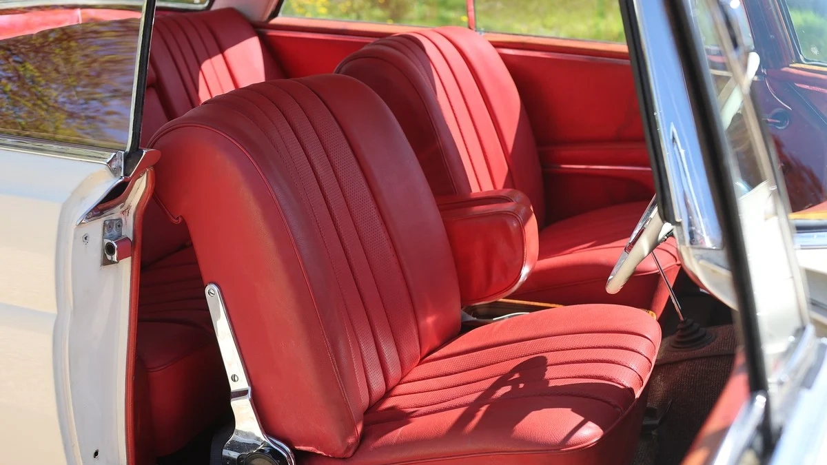 Open-door view of the Mercedes 250 SE Coupe showing burgundy red leather front seats.