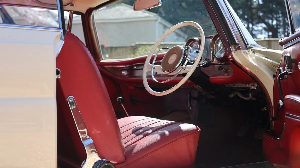 Interior view of Mercedes 250 SE Coupe with red leather seating, dashboard and steering wheel.