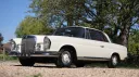 Low front side view of ivory Mercedes 250 SE Coupe parked outdoors with chrome grille and classic styling.