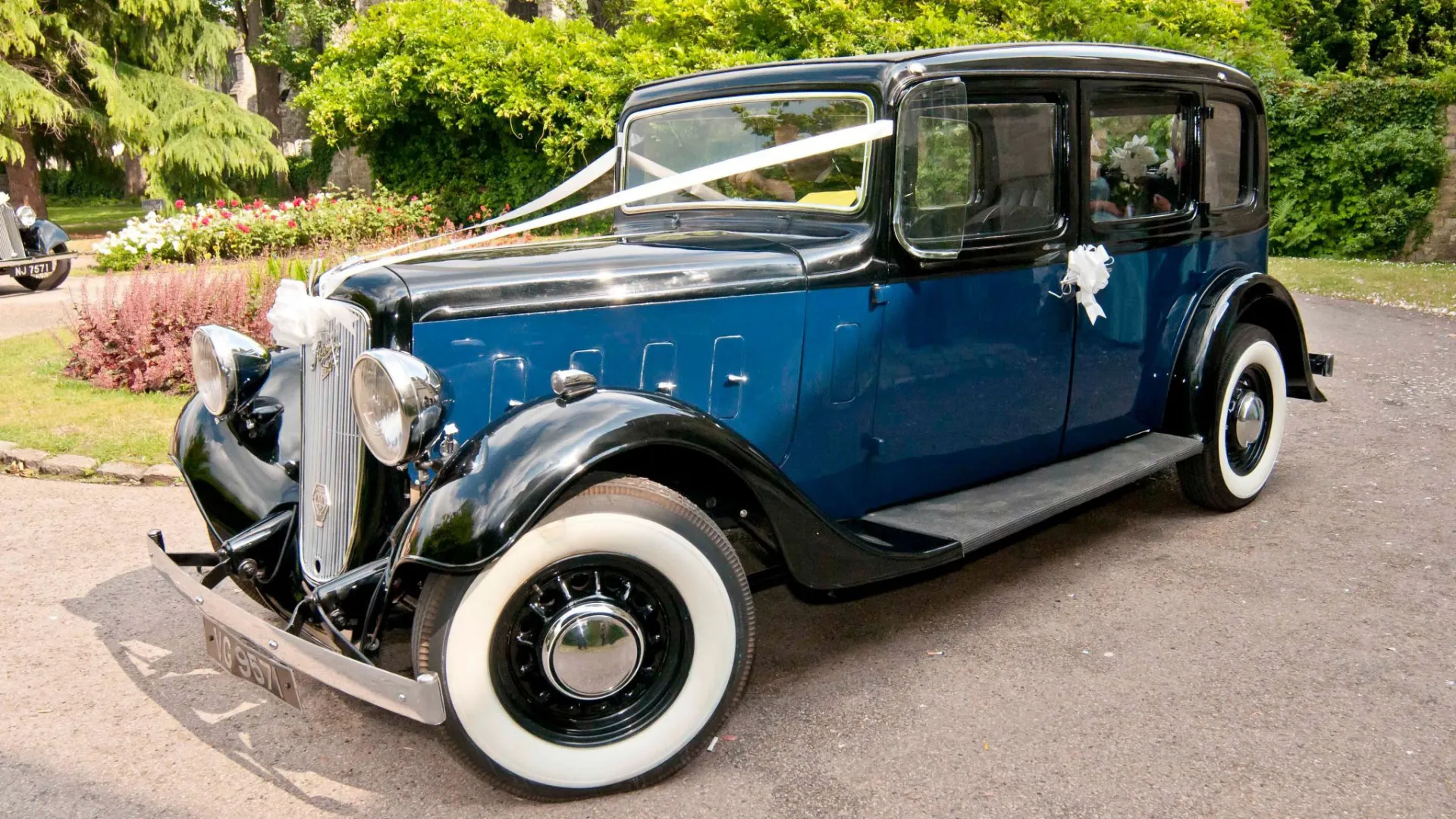 Blue Austin 18 York vintage wedding car with black roof and whitewall tyres parked at Kent wedding venue.