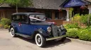 1930s blue Austin 18 York wedding car decorated with white ribbons outside countryside venue in Kent.